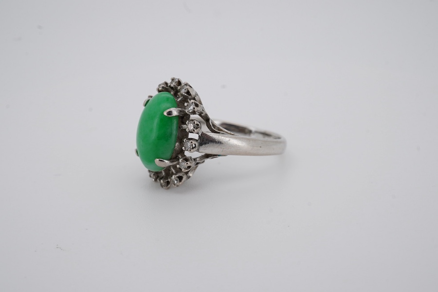 A white metal and cabochon jade set ring, with round cut diamond set border, size N, gross weight 5.4 grams. Condition - fair to good